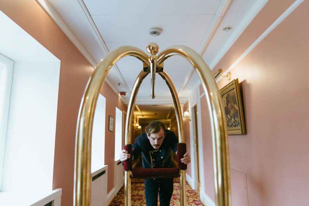 A bellboy pushes a luggage cart down a luxurious hotel corridor, embodying service and elegance.